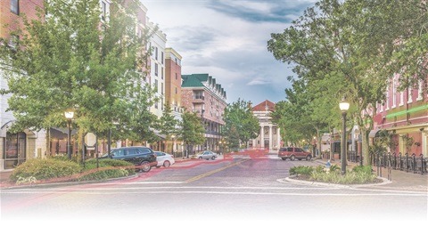 A picturesque downtown street in Gainesville, FL, resembling a watercolor painting, with the Hippodrome Theatre visible in the distance at the end of the road.