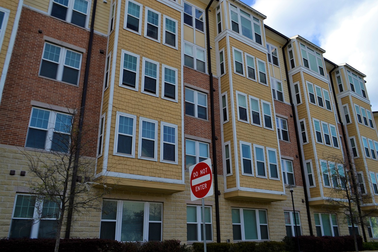 Street view of an apartment building, showcasing its architectural design and height as seen from below.