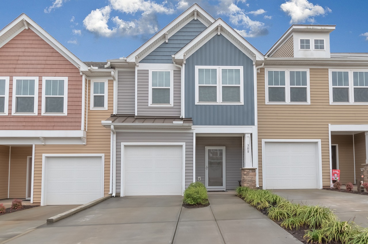 Three townhomes in a row with subtle color tones, all equipped with garages.